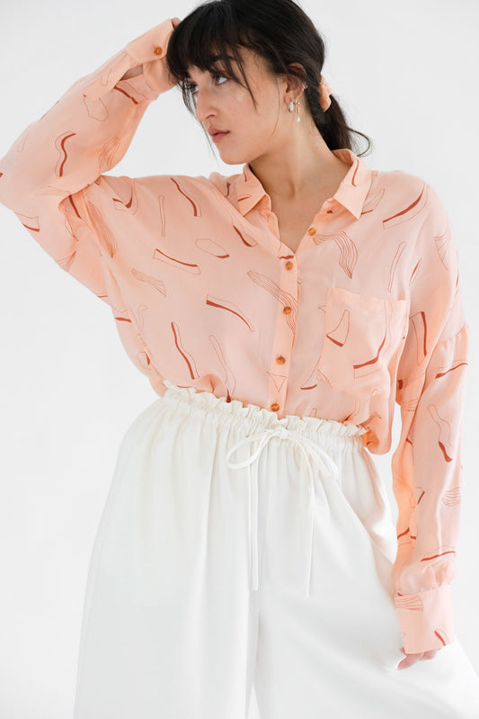 Girl wearing pink silk printed shirt and white trousers