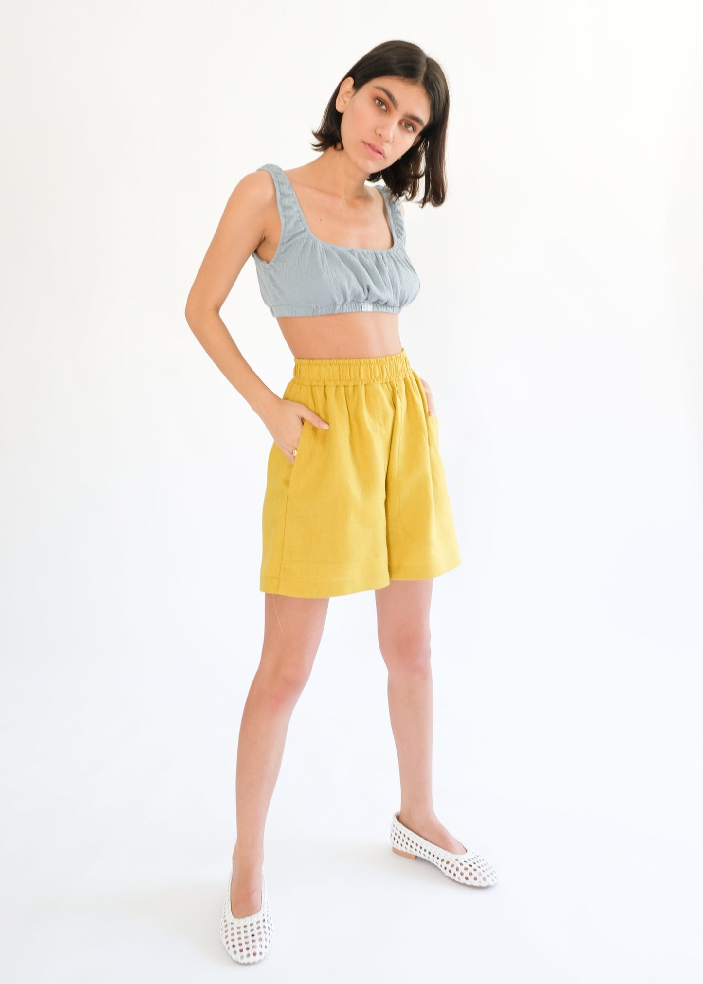 Girl standing wearing blue top and yellow shorts