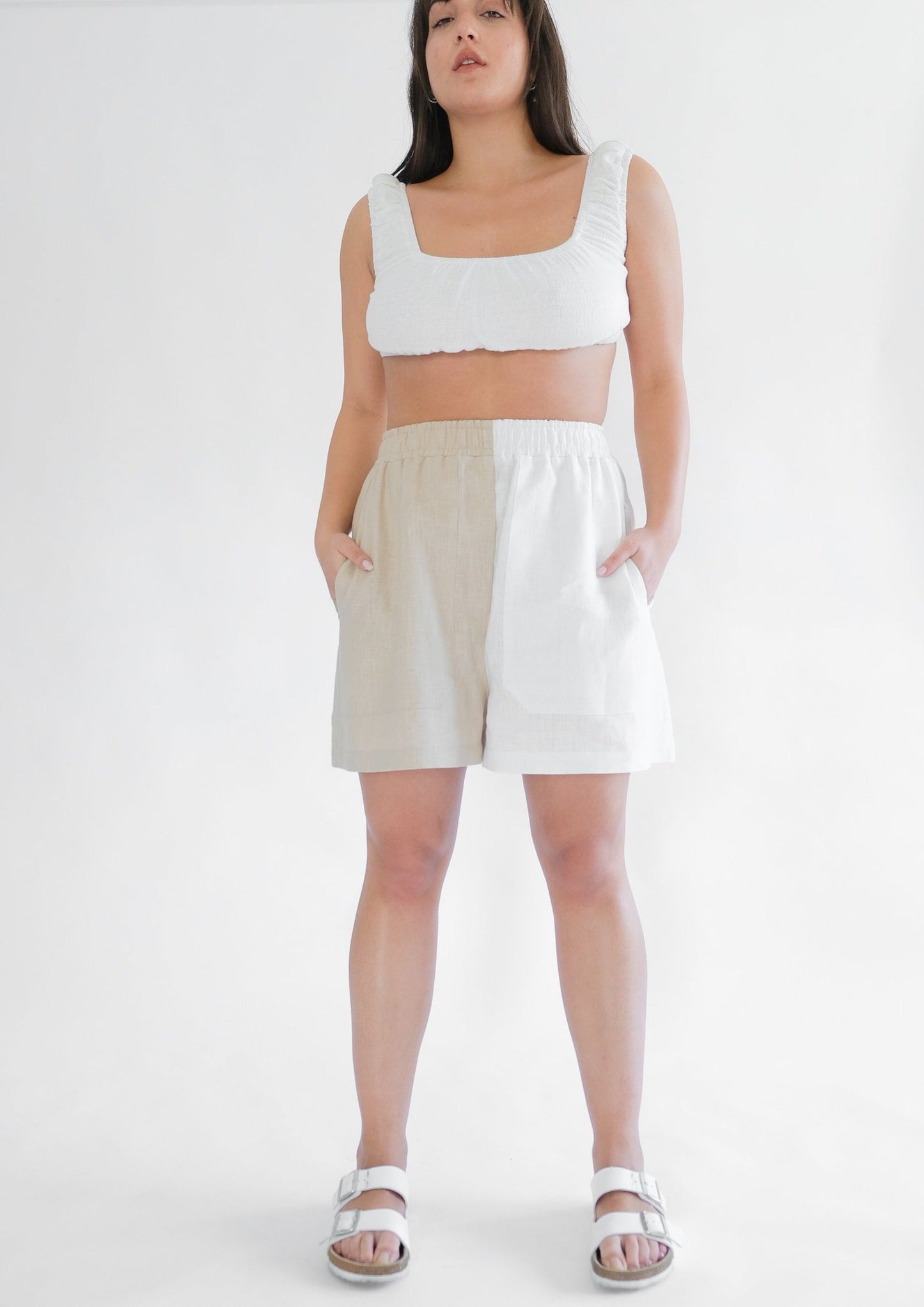 Girl standing wearing white top with brown and white shorts