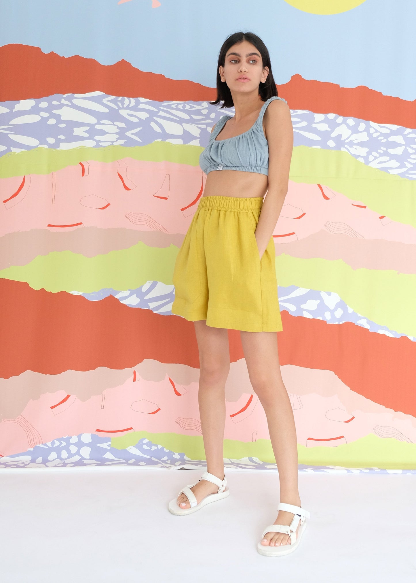 Girl standing wearing blue top and yellow shorts 