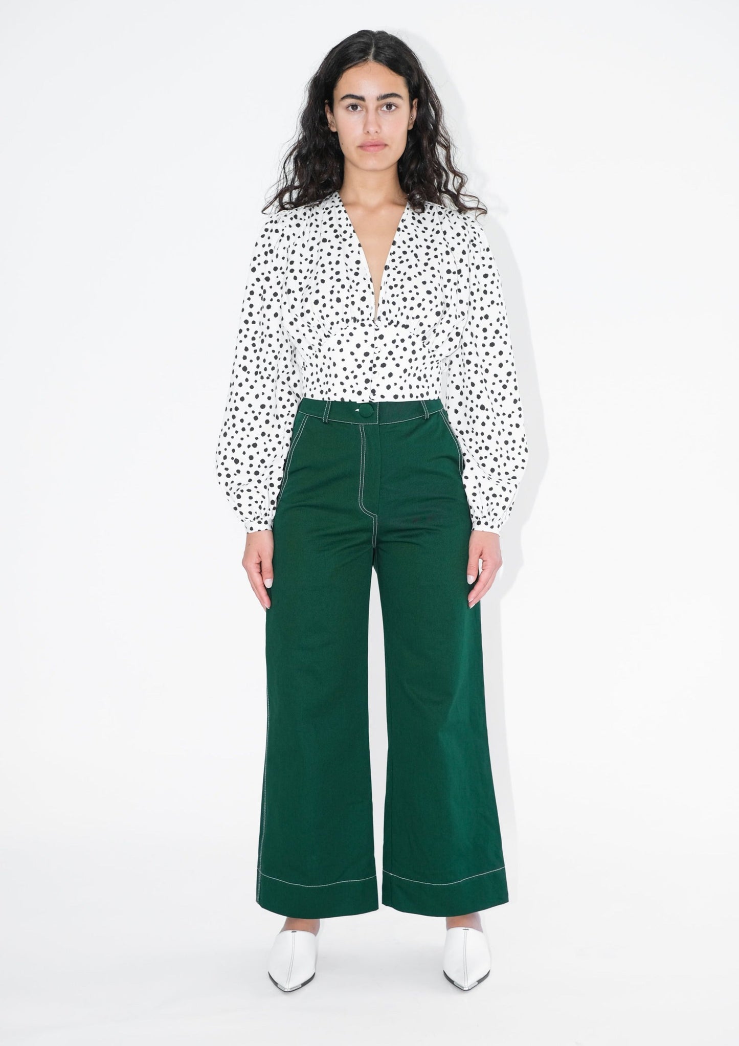 Woman wearing white shirt with black polka dots and green trousers