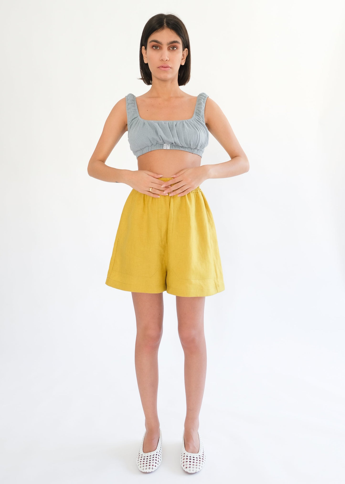 Girl standing wearing blue top and yellow shorts 
