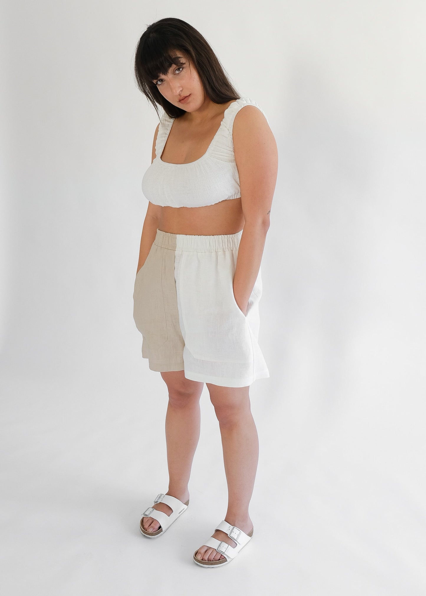 Girl standing wearing white top with brown and white shorts 