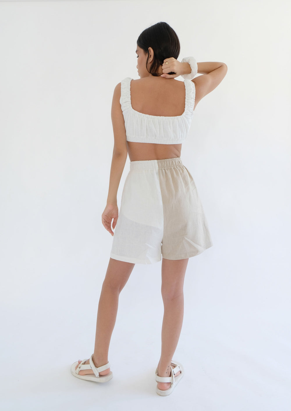 Girl standing backwards wearing white top with brown and white shorts 